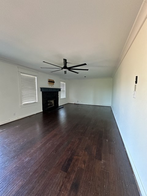 an empty living room with wood floors and a ceiling fan