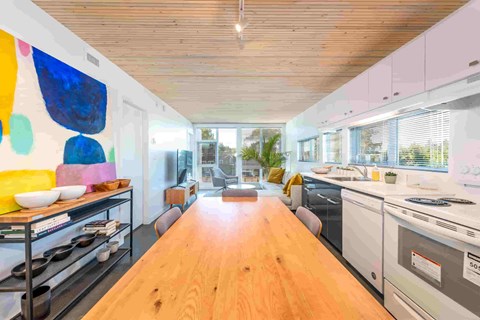 A modern kitchen with a wooden floor and a large painting on the wall.