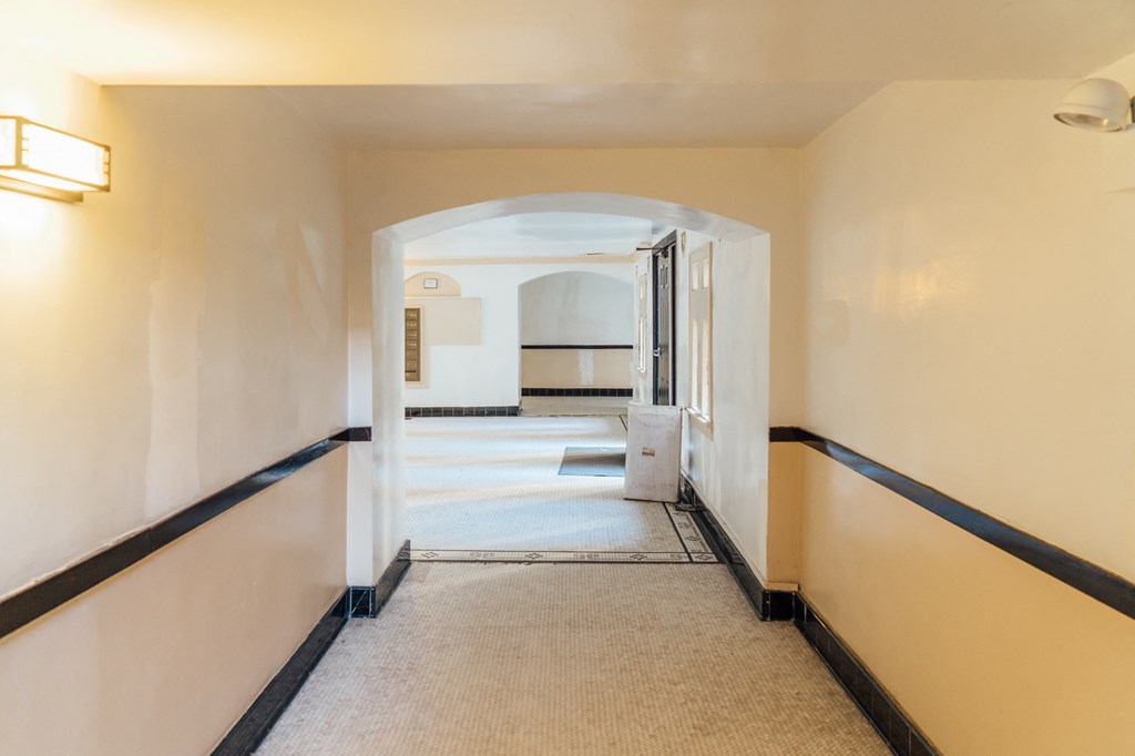 a hallway with white walls and a white carpeted floor and an open door