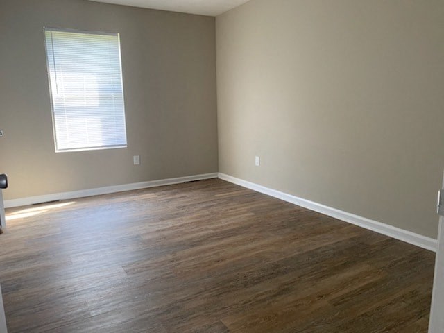 A room with wooden flooring and a window with blinds.