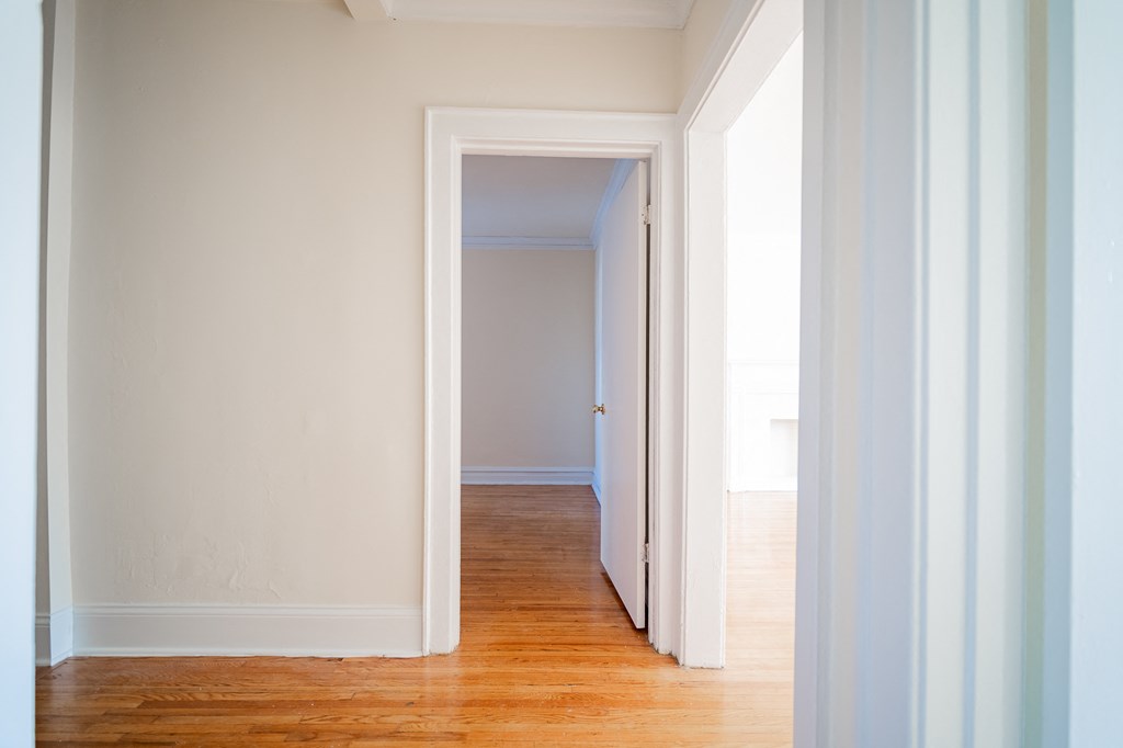 a hallway with wood floors and white walls and a door