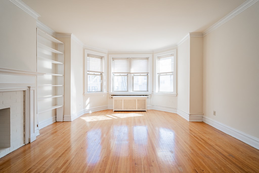 an empty living room with wood floors and a window