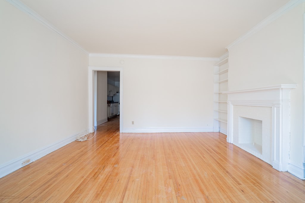 an empty living room with wood floors and a fireplace