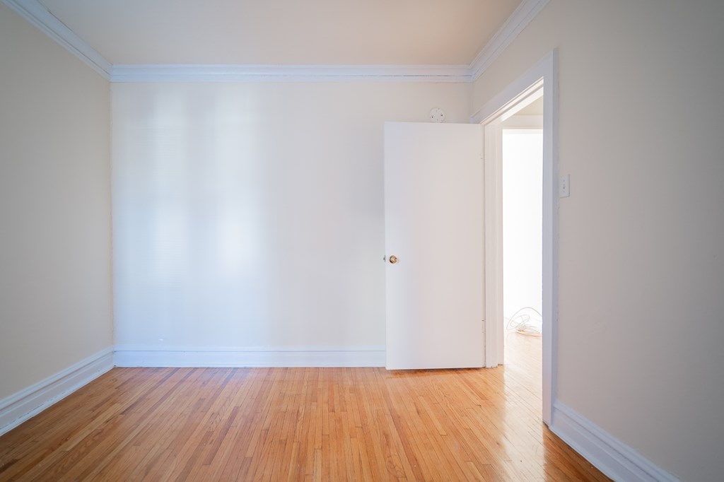 a room with white walls and a wooden floor and a white door