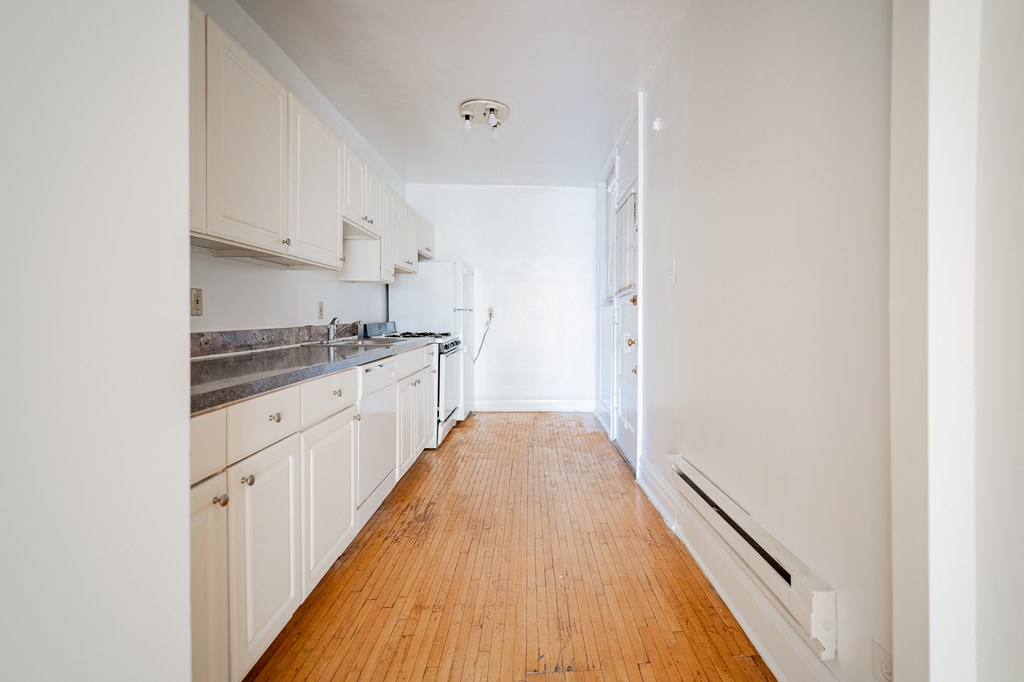 a kitchen with white cabinets and a wood floor