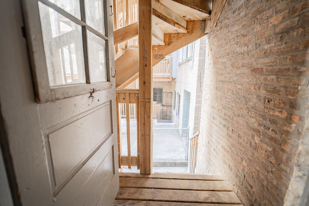 the stairway up to the second floor of a house with wood and brick walls