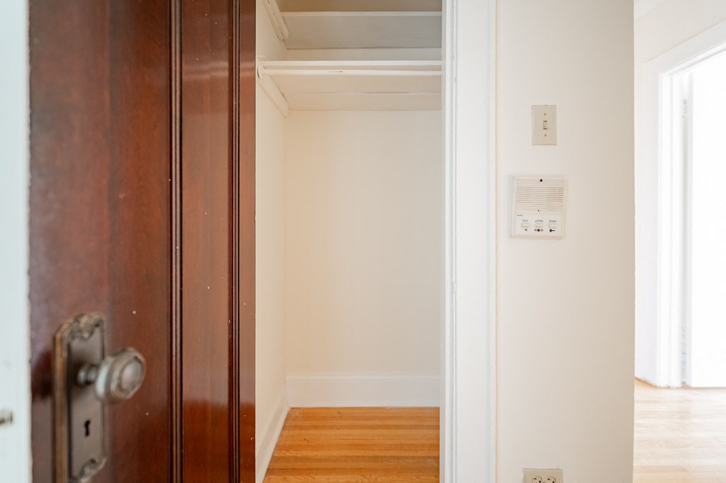 a wooden door is open to a hallway with white walls and wood floors