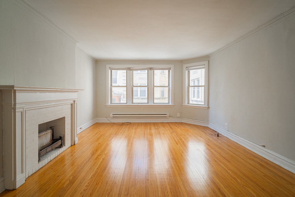 an empty living room with a fireplace and wooden floors