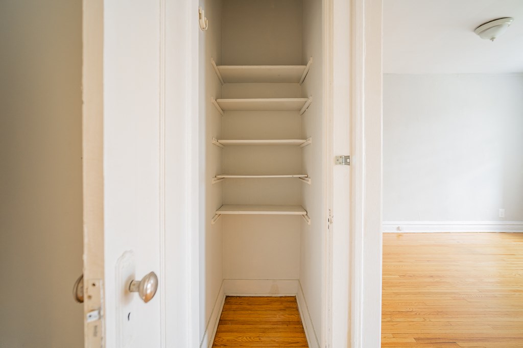 a small closet in a room with wooden floors and empty shelves