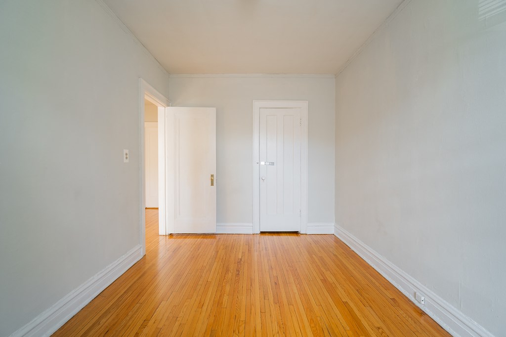 a living room with wood floors and white walls and two doors