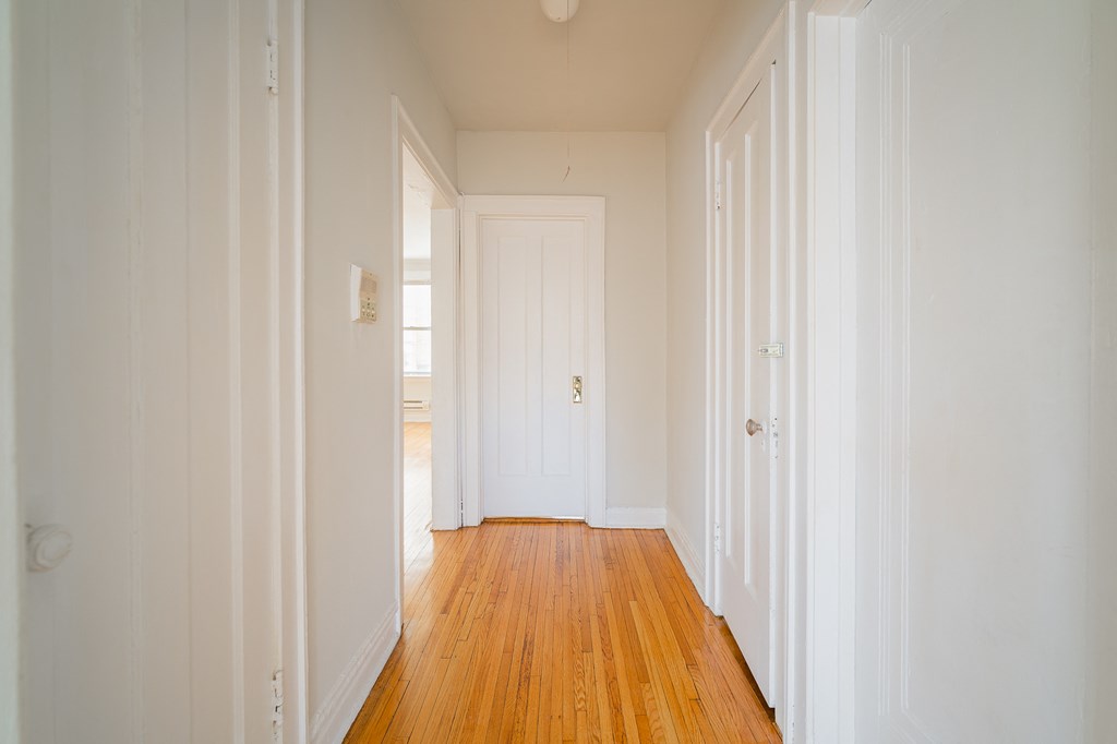 a room with white walls and wooden floors and a white door
