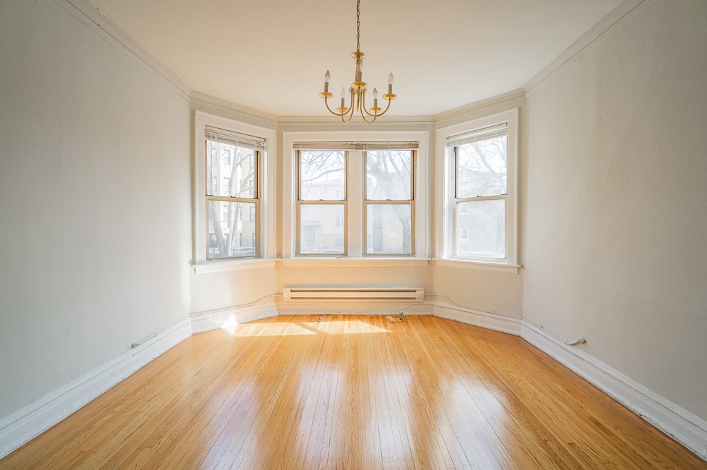 an empty living room with a chandelier and three windows