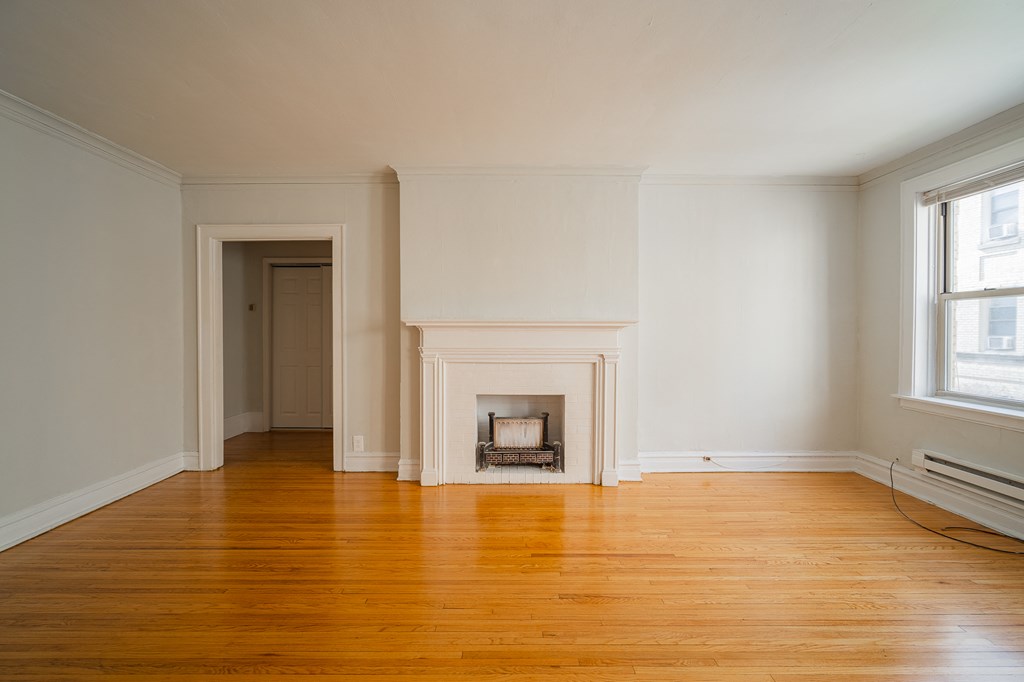 an empty living room with a fireplace and wooden floors