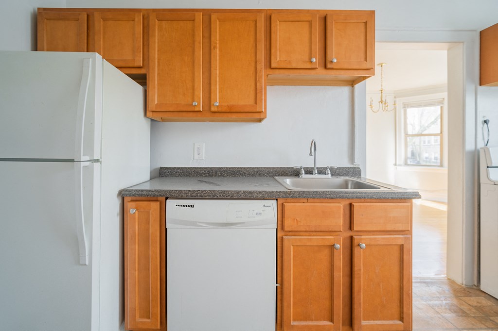 an empty kitchen with wooden cabinets and a white dishwasher