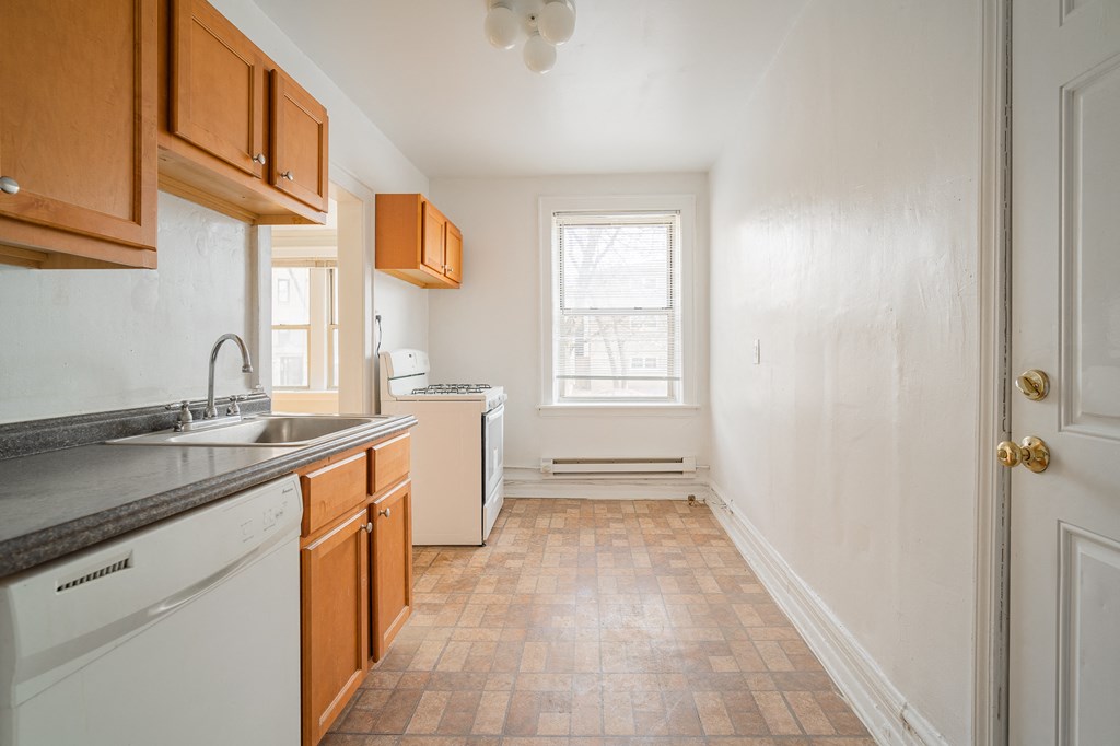 a kitchen with white appliances and wooden cabinets and a window