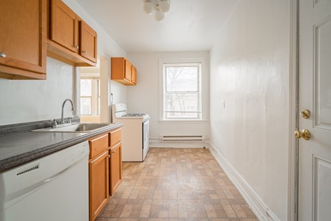 a kitchen with white appliances and wooden cabinets and a window