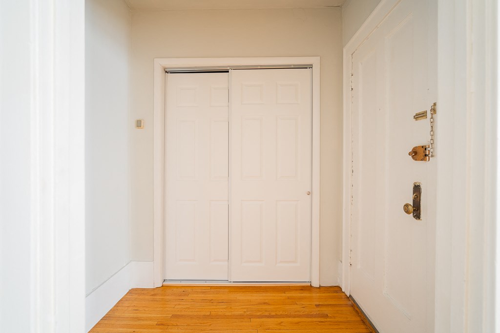 a room with a white door and a wood floor and a closet