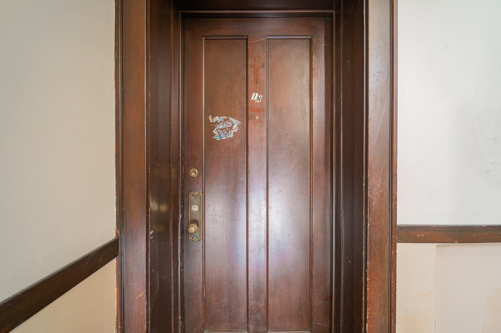 a wooden door with a sticker on it next to a staircase