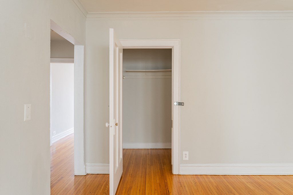 an empty room with a door open to a closet