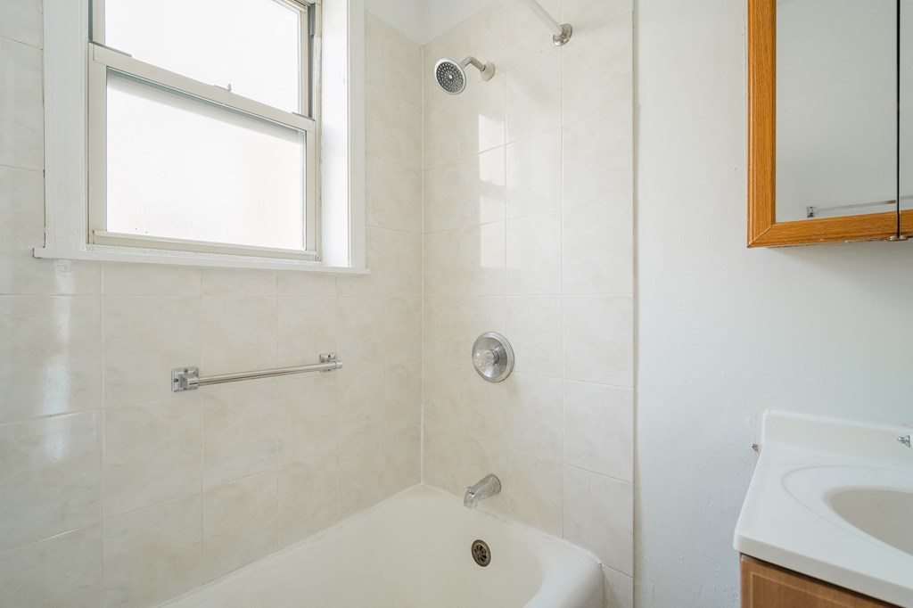 a bathroom with a shower and a sink and a window