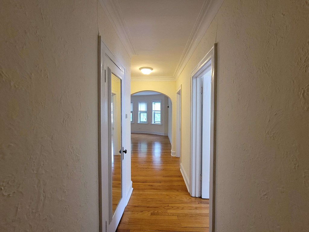 a hallway with wood floors and white walls and a window