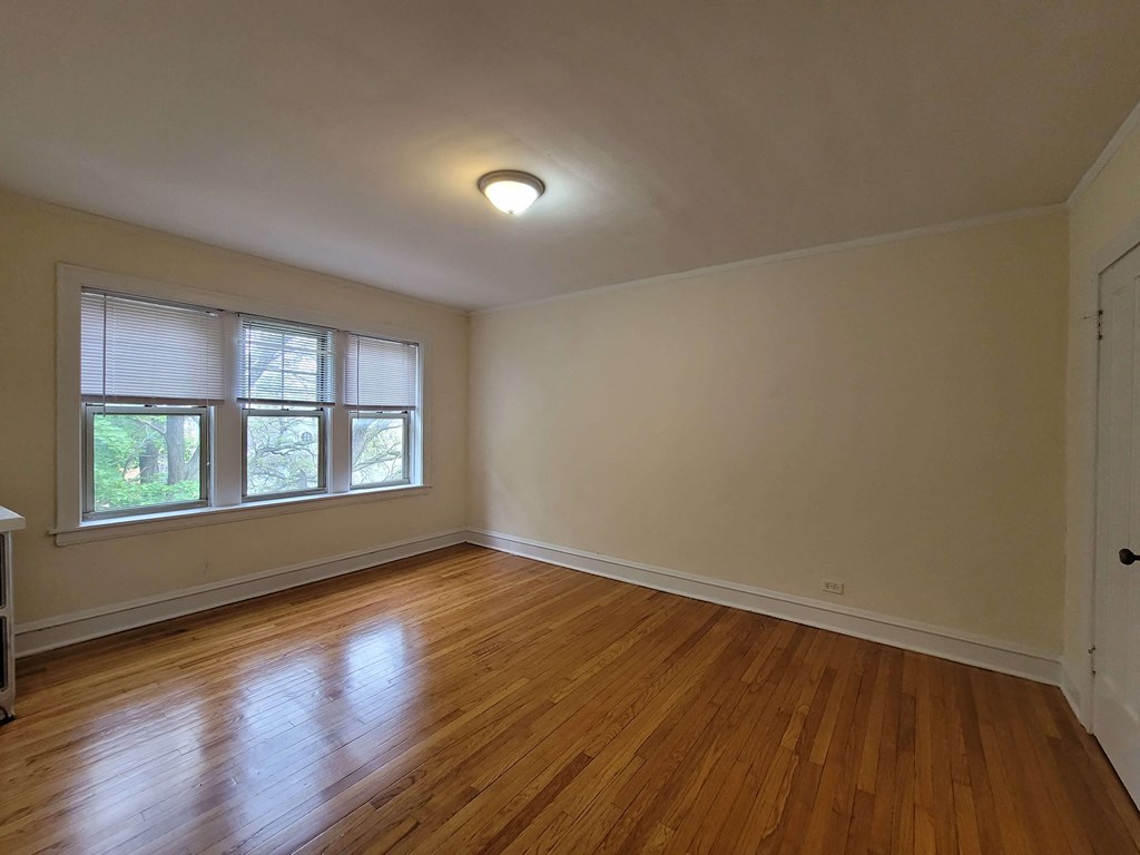 an empty living room with wood floors and a window