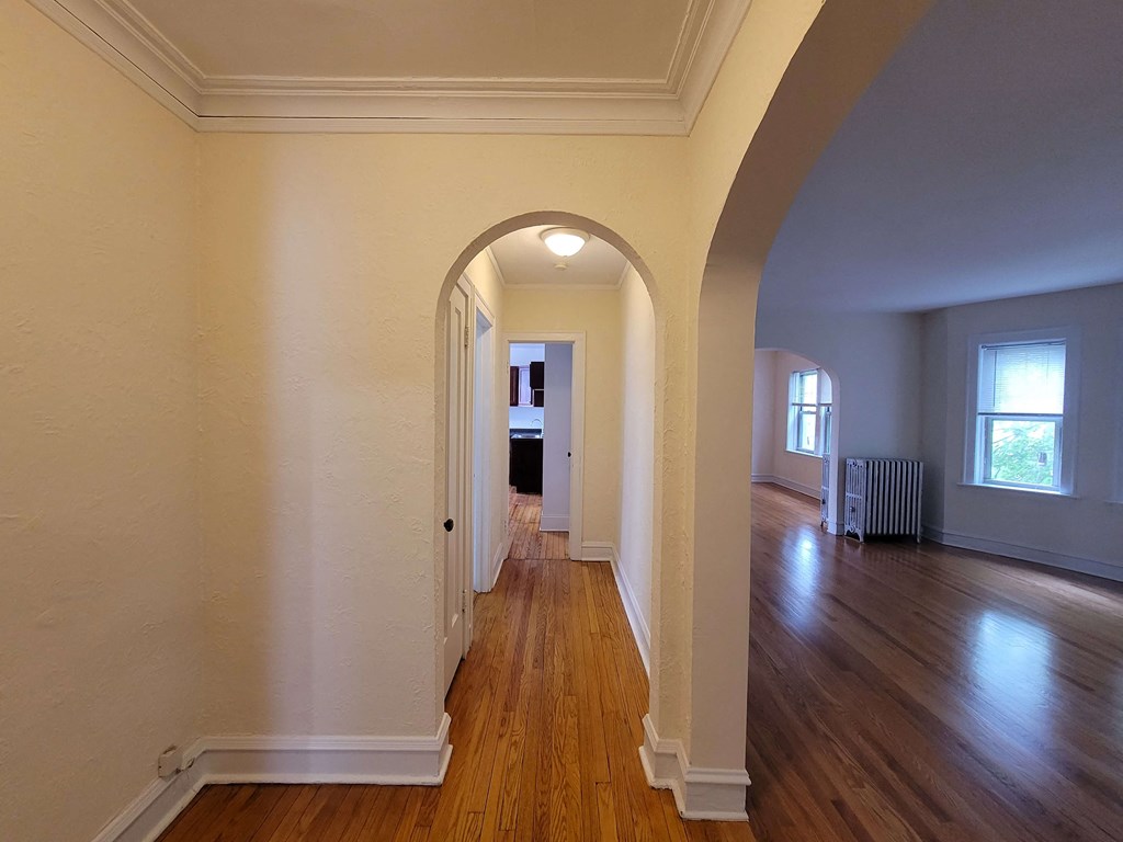 an empty living room with an archway and wood floors