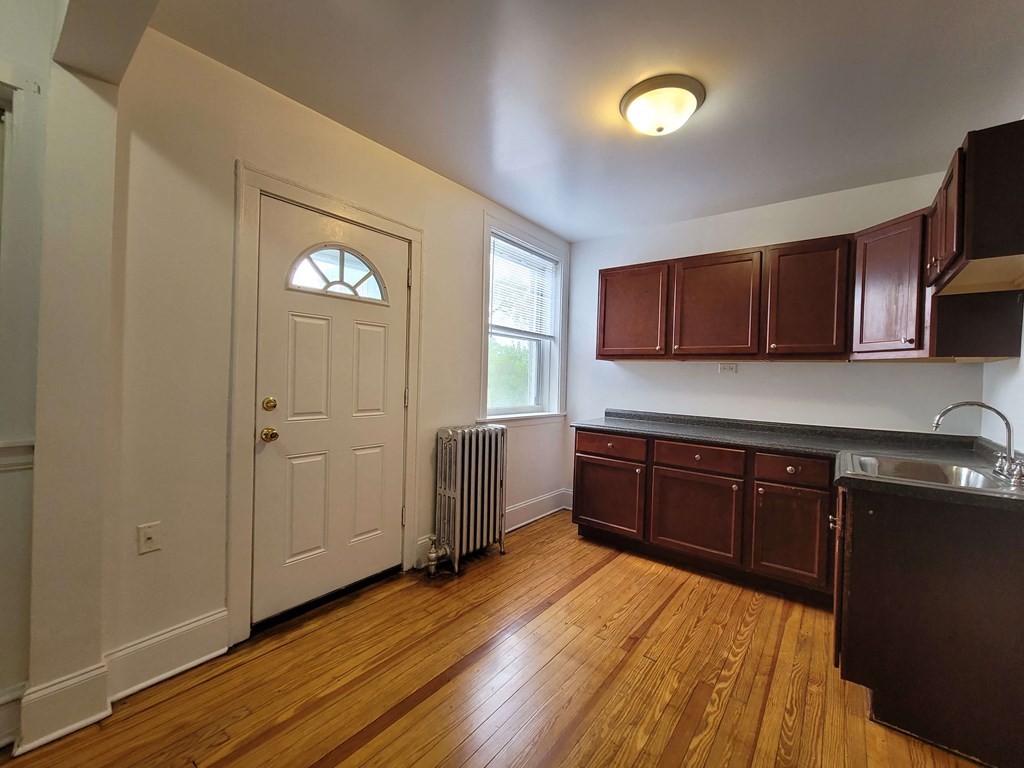 an empty kitchen with wooden floors and a white door