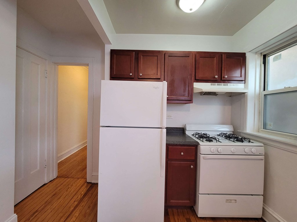 a kitchen with white appliances and brown cabinets and a white refrigerator