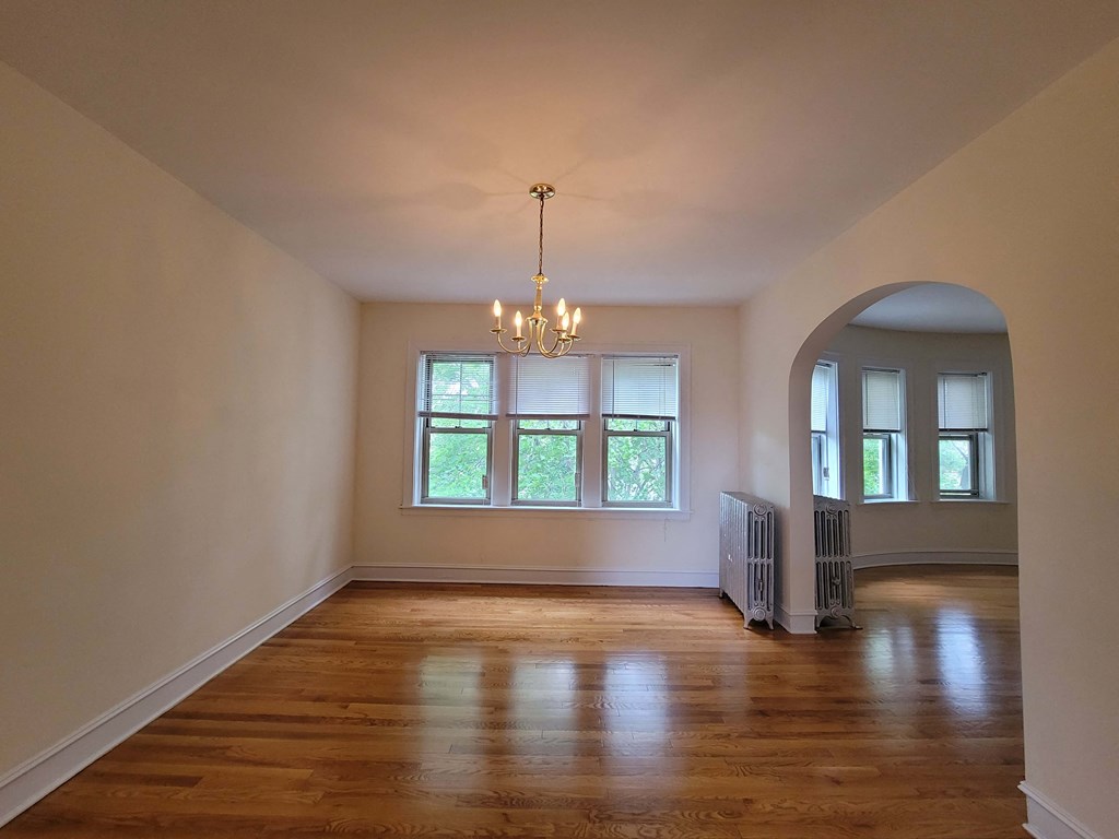 an empty living room with a large window and a chandelier