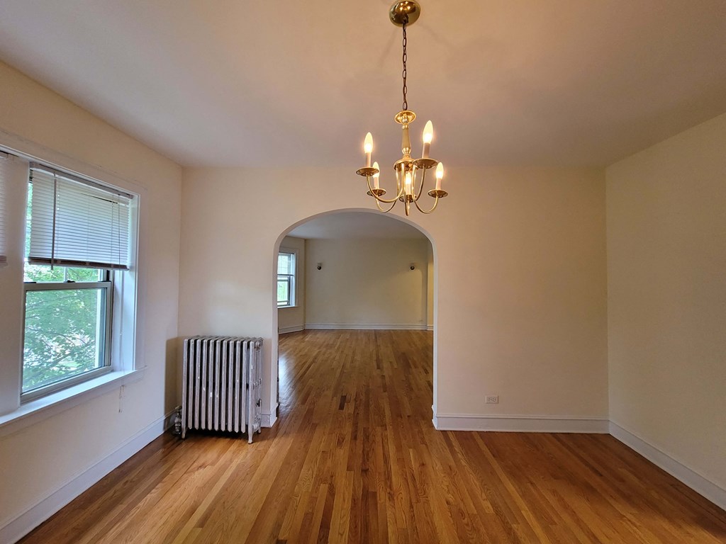 an empty living room with a radiator and a chandelier