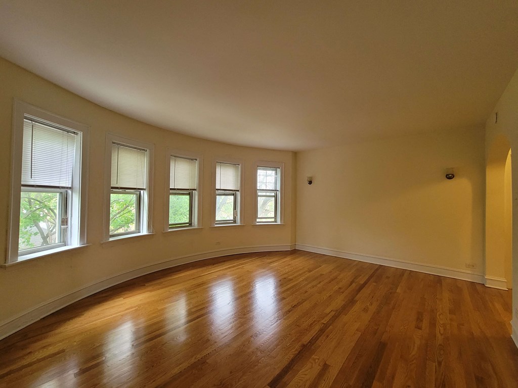an empty living room with wooden floors and windows