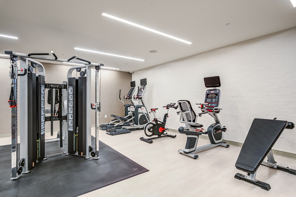 a gym with cardio equipment and weights in a building with white walls