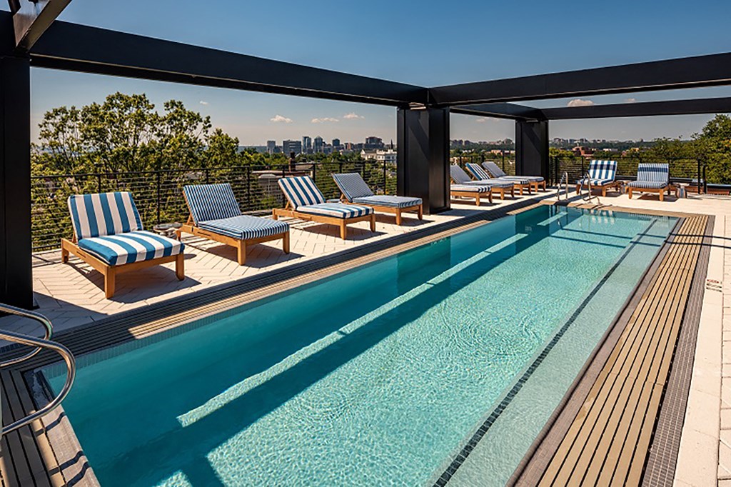 a swimming pool with lounge chairs on top of a building