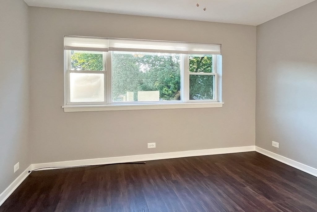 A room with a window and wooden flooring.