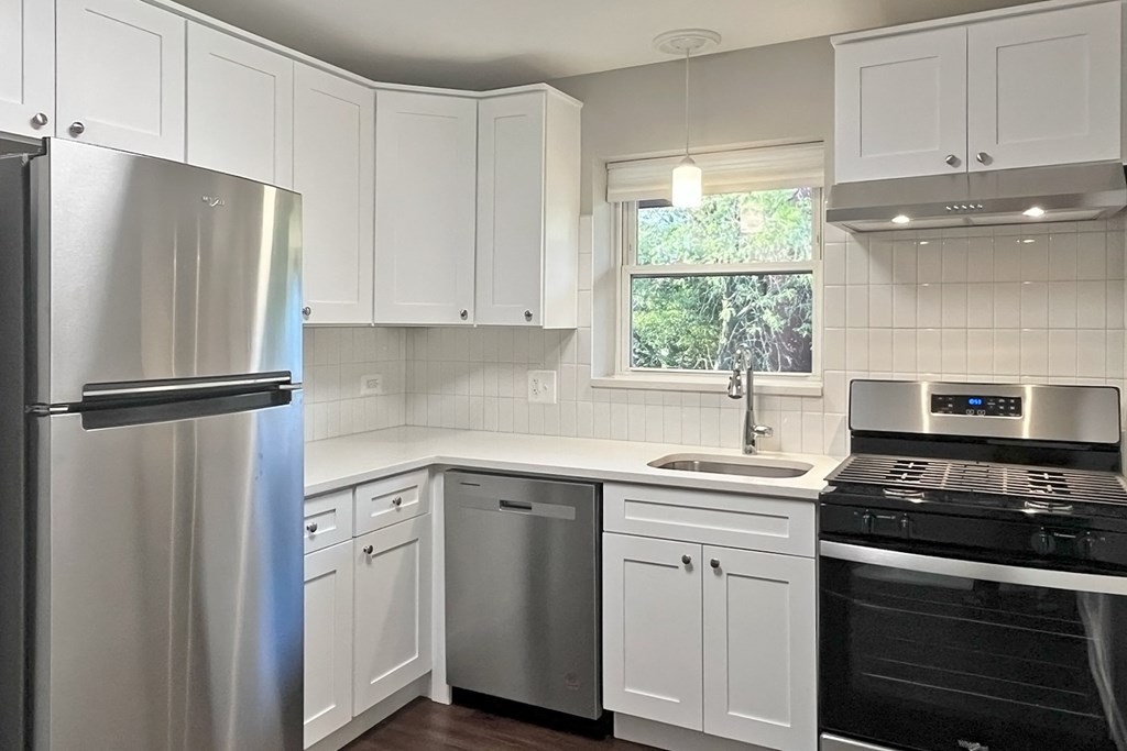 A kitchen with white cabinets and a stainless steel refrigerator.