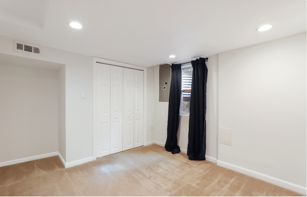 a living room with white walls and a window with black curtains