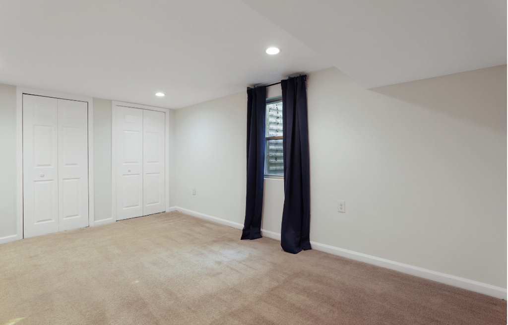 a bedroom with white walls and a window with black curtains