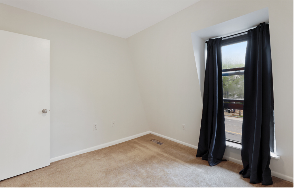 a room with white walls and a window with black curtains