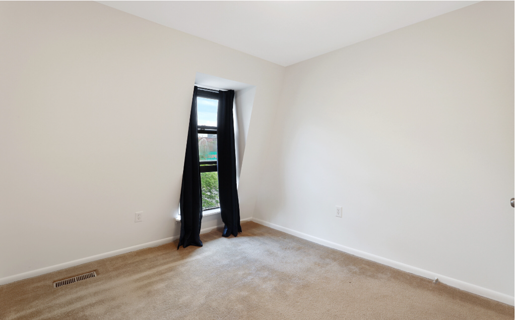 an empty room with a window and a curtain