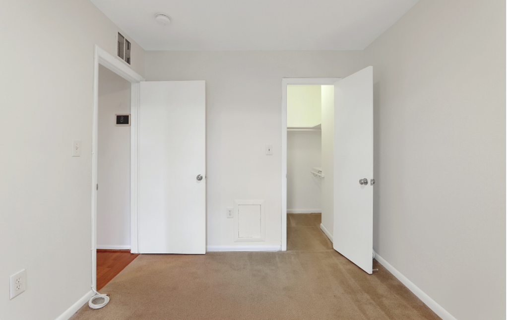 a bedroom with white walls and white doors and a carpeted floor