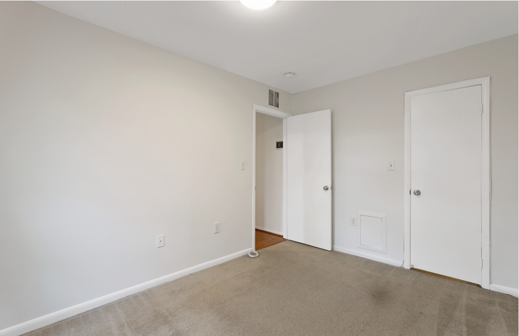 a bedroom with white walls and white doors and a carpeted floor