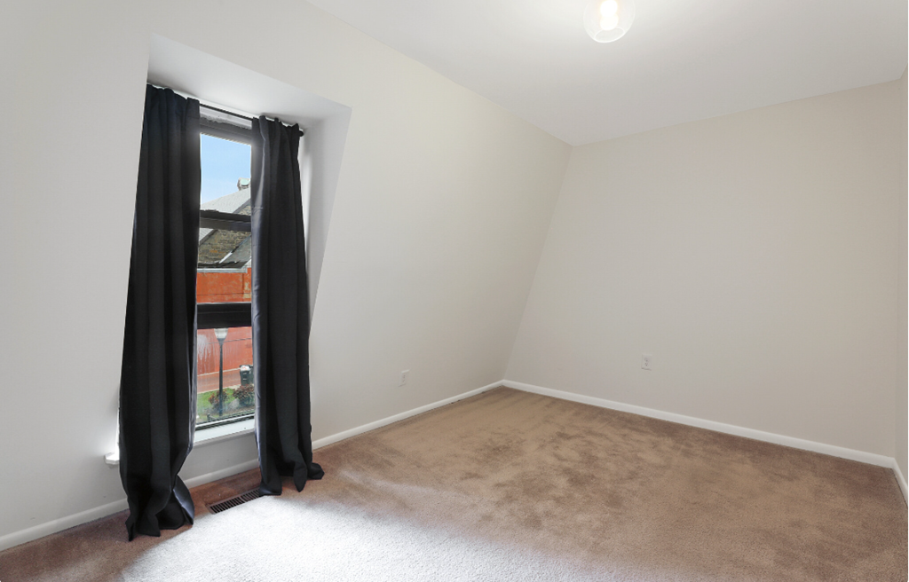 an empty room with black curtains and a window