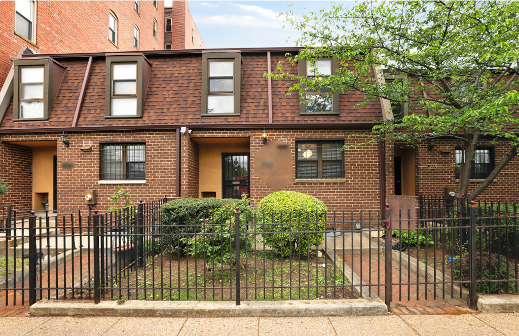 a brick apartment building with a yard and a wrought iron fence