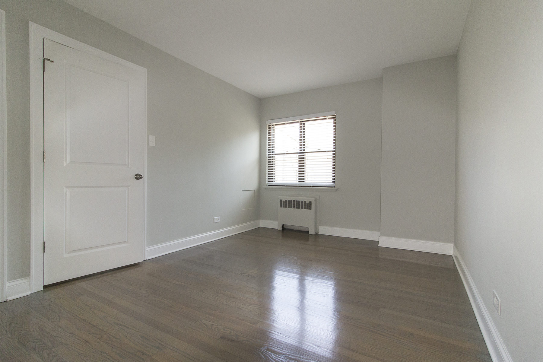 an empty living room with a white door and a window