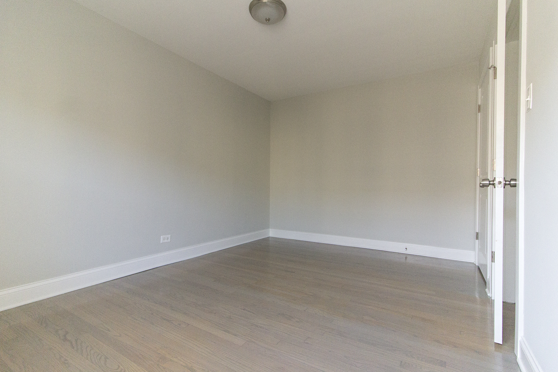 an empty room with white walls and wood floors