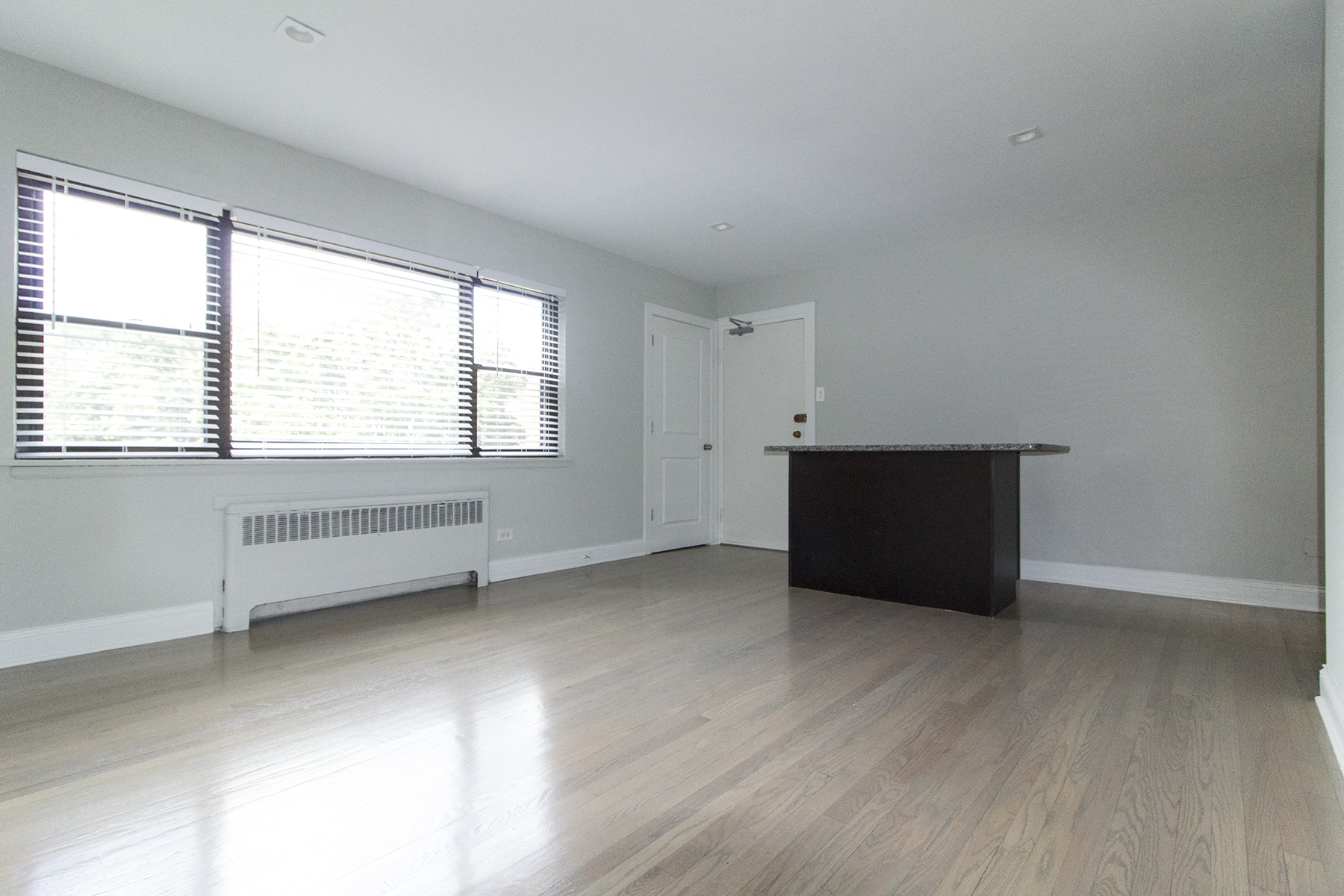 an empty living room with a desk and a window