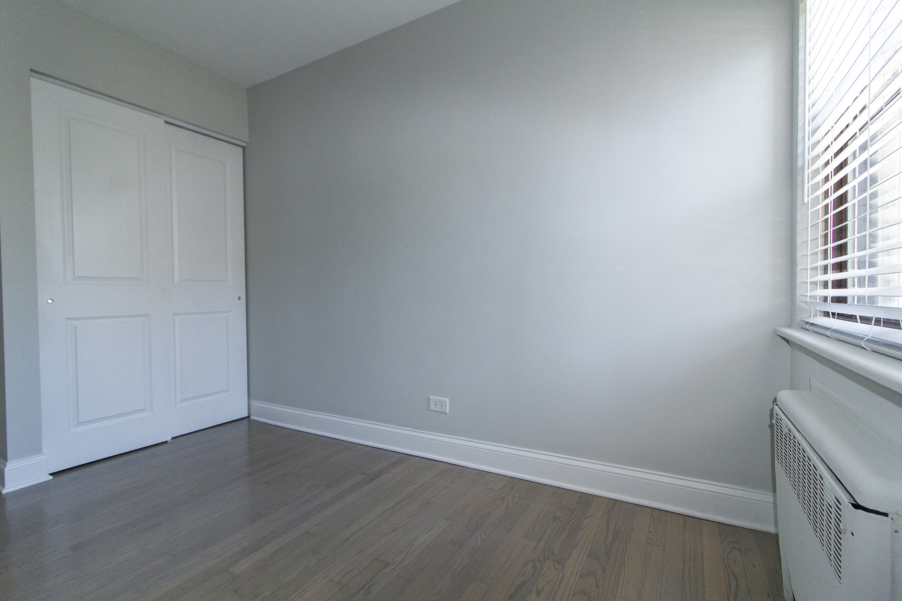 an empty living room with wood floors and a white door