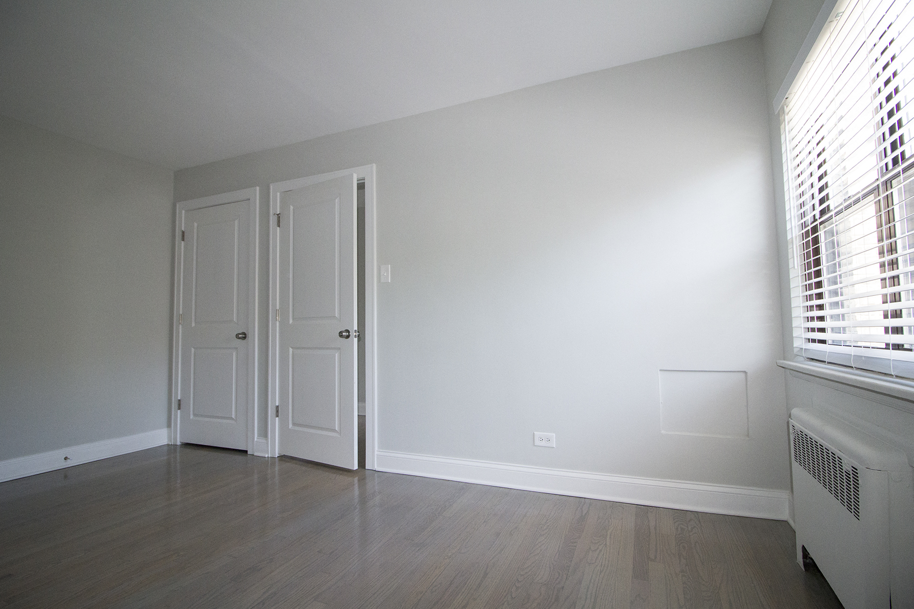 an empty living room with white walls and wood flooring
