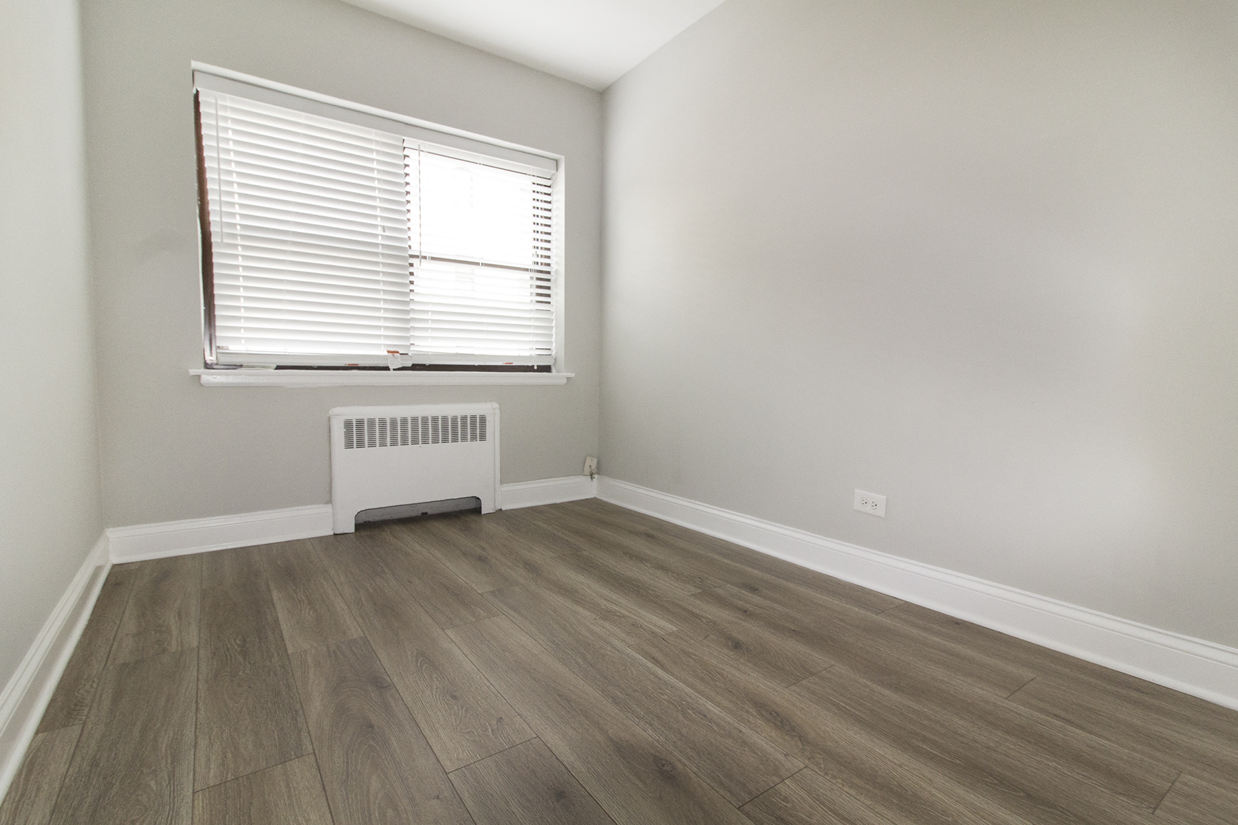 an empty room with wood floors and a window